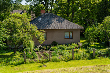 cozy countryside house with garden in summer surrounded by green trees and wooden fence peaceful rural home backyard vegetation small village real estate nature living exterior landscape scene
