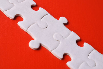 White puzzle pieces forming a line on red background