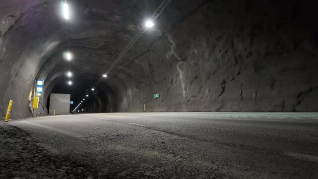 Cyclist traversing the dimly lit 5900m F&aacute;skr&uacute;&eth;sfjar&eth;arg&ouml;ng tunnel in Iceland, showcasing the unique underground infrastructure