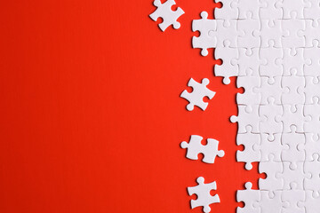 White puzzle pieces on red background, top view. Space for text