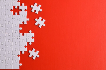 White puzzle pieces on red background, top view. Space for text