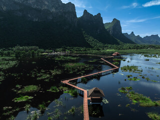 Wooden Bridge and red resting pavilion in lotus lake and mountain peak with blue sky backgrounds at...