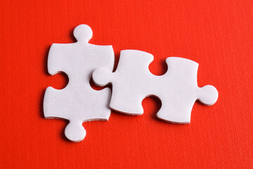 Obraz premium Two white puzzle pieces on a red background. Top view