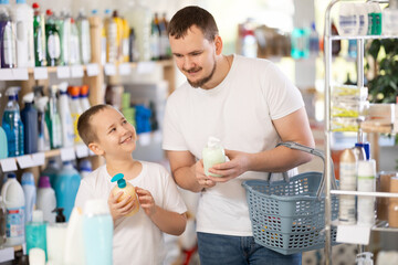 Dad tells son about choosing liquid hand soap with batcher, shows him packaging of suitable...