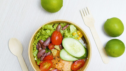 Healthy poke bowl with grilled salmon, rice, beans, cherry tomatoes, cucumber, lettuce, corn,...