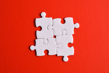 Four puzzle pieces on red background. The concept of finding the right solutions in teamwork.