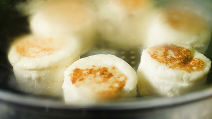 Delicious cheese pancakes are steaming in a steamer basket, their tops perfectly browned and filling the air with a mouth watering aroma, creating an inviting breakfast or brunch option