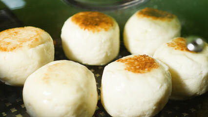 Round cheese pancakes frying in a pan, creating a mouthwatering breakfast delight with perfectly golden brown tops. The aroma fills the kitchen, promising a delicious start to the day