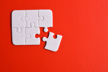 White puzzle pieces on red background. Flat lay. Top view