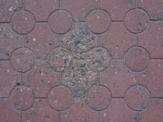 Close-up of pavement texture with worn red rectangular and round paving slabs with arranged in a uniform pattern.