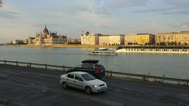 BUDAPESHT - JUL 21, 2019: Boat is traveling down a river near a city. The boat is white and blue. The river is calm. Budapest, Hungary