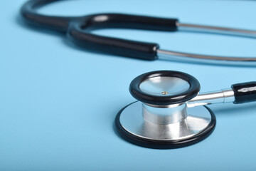 Stethoscope on light blue background, closeup