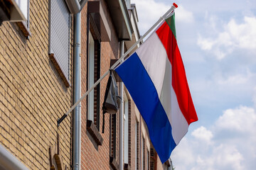 Official Netherlands flag with a school bag hanging outside the house along the street with blue...
