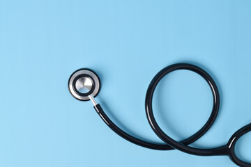 Stethoscope on light blue background, top view, closeup. Space for text