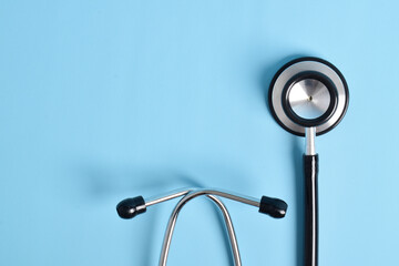 Stethoscope on light blue background, top view, closeup. Space for text