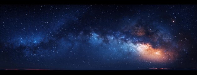 Panoramic night sky filled with countless stars and a bright, colorful band of the Milky Way galaxy stretching across the horizon over a dark silhouette of the landscape