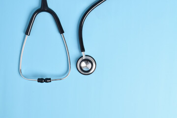 Stethoscope on light blue background, top view, closeup. Space for text