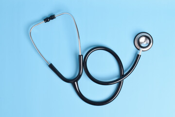 New stethoscope on light blue background, top view. Medical instrument
