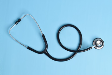 New stethoscope on light blue background, top view. Medical instrument