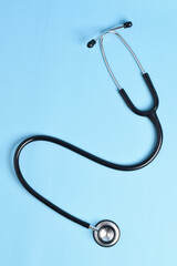New stethoscope on light blue background, top view. Medical instrument