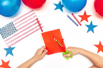 Child's hands cuts out stars with scissors for Independence day America.Kid making flag of...