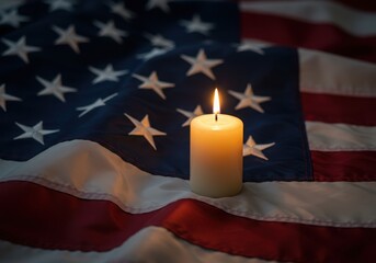 A lit candle casts a warm glow upon the stars and stripes of the american flag symbolizing remembrance and honor