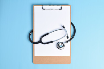 Blank medical clipboard with stethoscope on light blue background