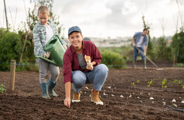 Farmer woman and her son plant seeds and garlic on the farm. Planting farm vegetables