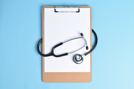 Blank medical clipboard with stethoscope on light blue background