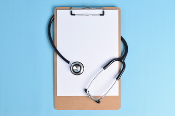 Blank clipboard with stethoscope on light blue background. World Health Day