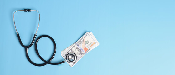 Black stethoscope and US dollar bills on light blue background, symbolizing medical costs, healthcare financing, and insurance expenses in the healthcare industry.
