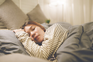 A tired woman wakes early with a headache, struggling with insomnia and fatigue. Low light, stress,...