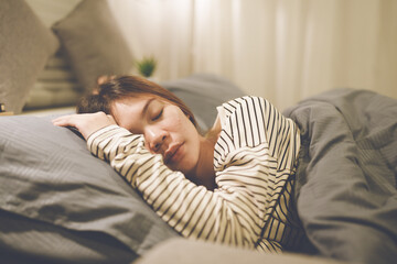 A tired woman wakes early with a headache, struggling with insomnia and fatigue. Low light, stress,...