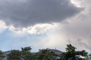 Obraz premium Dramatic Clouds Over Forested Landscape With Sunbeams Streaming Through Gaps