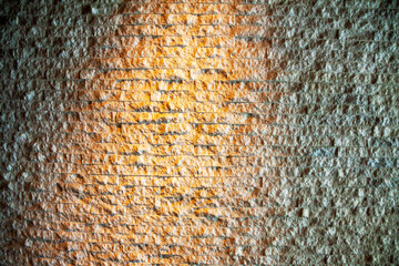 オレンジのライトが反射する石組みの壁の表面