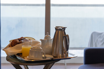 
Breakfast with coffee orange juice and croissants on a basket on table at cabin in cruise ship