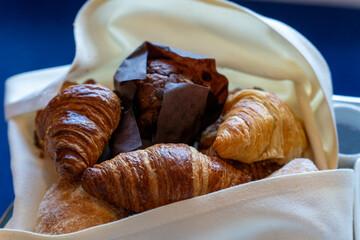 
Breakfast with chocolate muffin and croissants on a basket on table at cabin in cruise ship