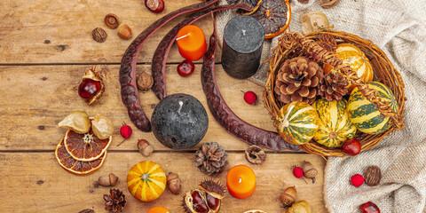 Autumn cozy composition. Pumpkins in a basket, candles, cones, seeds. Traditional fall decor