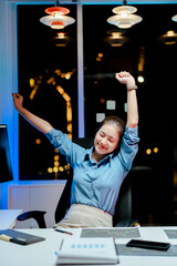 Smiling female programmer relaxing late at night with completed work. Software developer working on new project in office.
