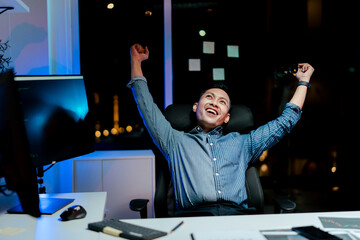 Male programmer relaxes late at night with completed work. Software developer working on new project in office.