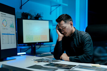Portrait of a man working overtime at the office. Employee working hard, stressed, tired, working slowly.