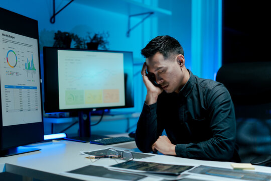 Portrait of a man working overtime at the office. Employee working hard, stressed, tired, working slowly.