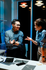 Male and female coworkers are working and analyzing projects in the office late at night.