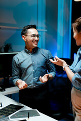 Male and female coworkers are working and analyzing projects in the office late at night.