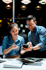 Male and female coworkers are working and analyzing projects in the office late at night.