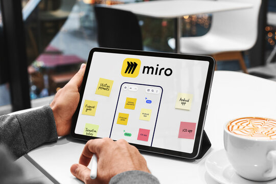 Businessman using miro app for project management on digital tablet in cafe