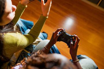 Two women enjoying video games at home, laughing and sharing joy while competing with joypads in hand, creating lasting memories together
