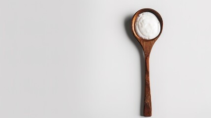 A wooden spoon dipped in creamy yogurt, standing isolated on a spotless white background. This image is a great fit for food - related projects, such as dairy product promotions, healthy eating guides