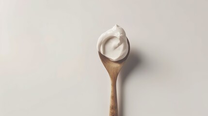 A wooden spoon dipped in creamy yogurt, standing isolated on a spotless white background. This image is a great fit for food - related projects, such as dairy product promotions, healthy eating guides