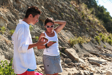 A teenager and his mother closely examine a snack while enjoying a leisurely moment outdoors near a...